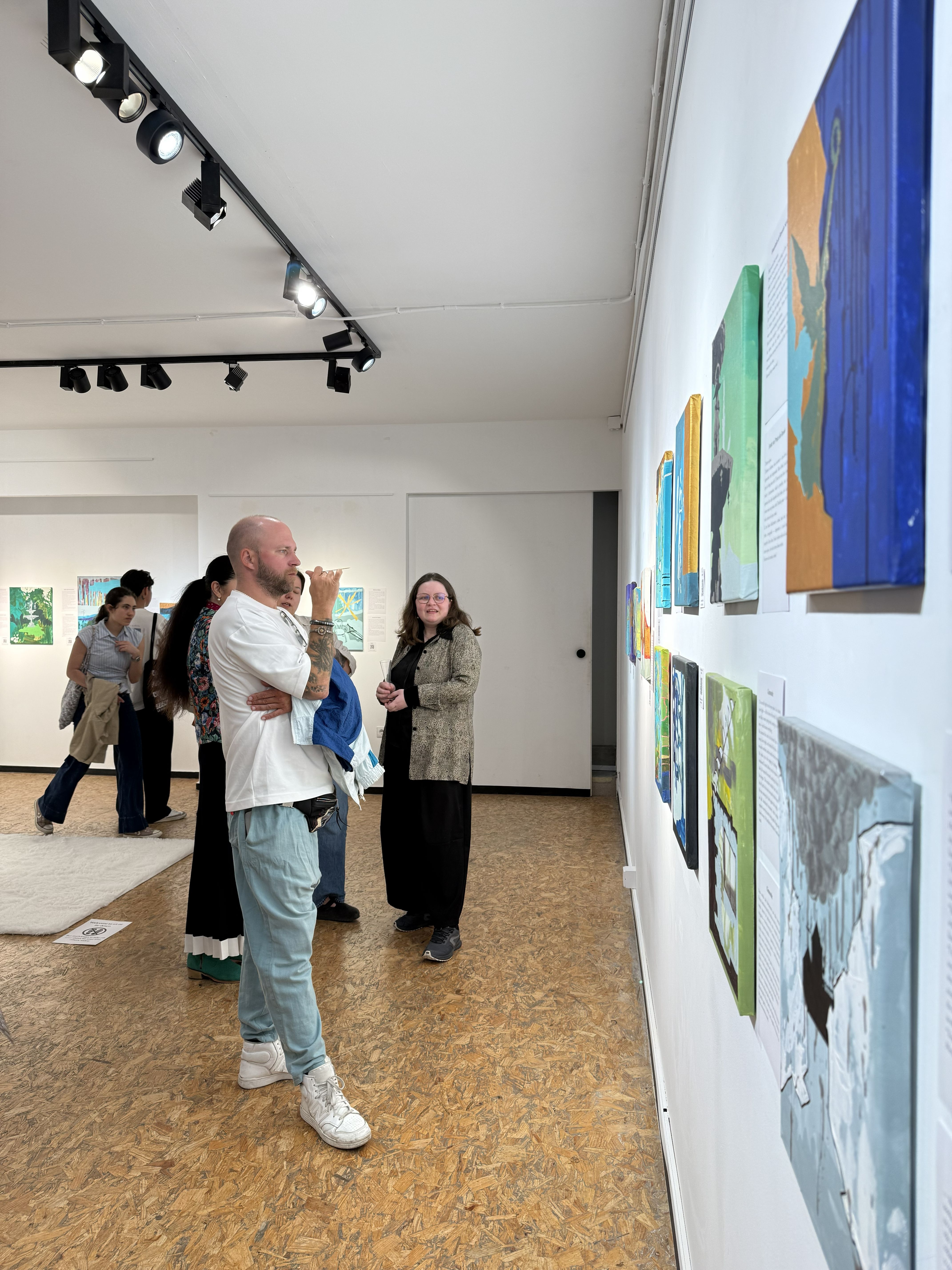 Several people in a big room with paintings