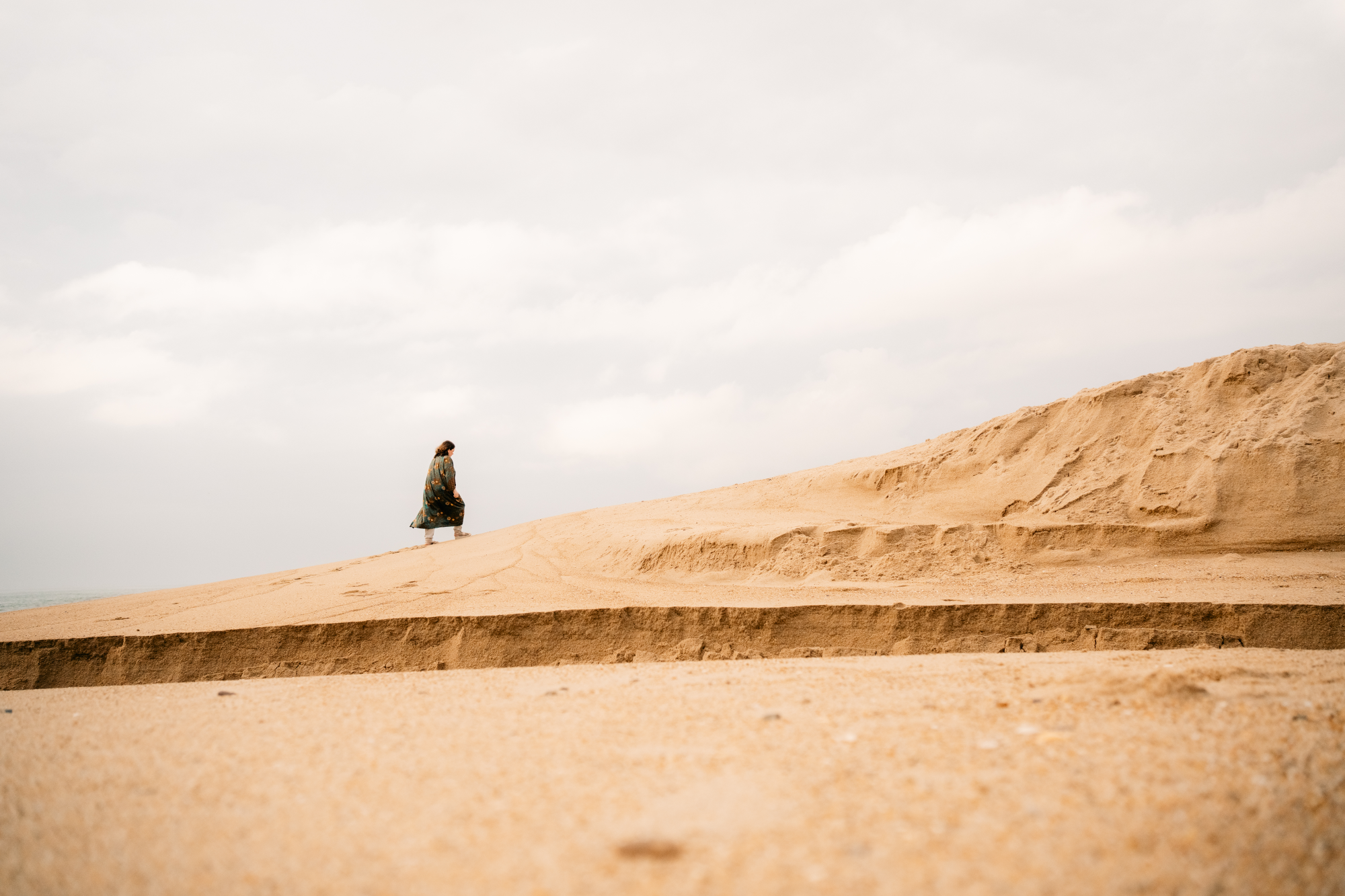 A way forward Artist in a robe walking up the sand dune